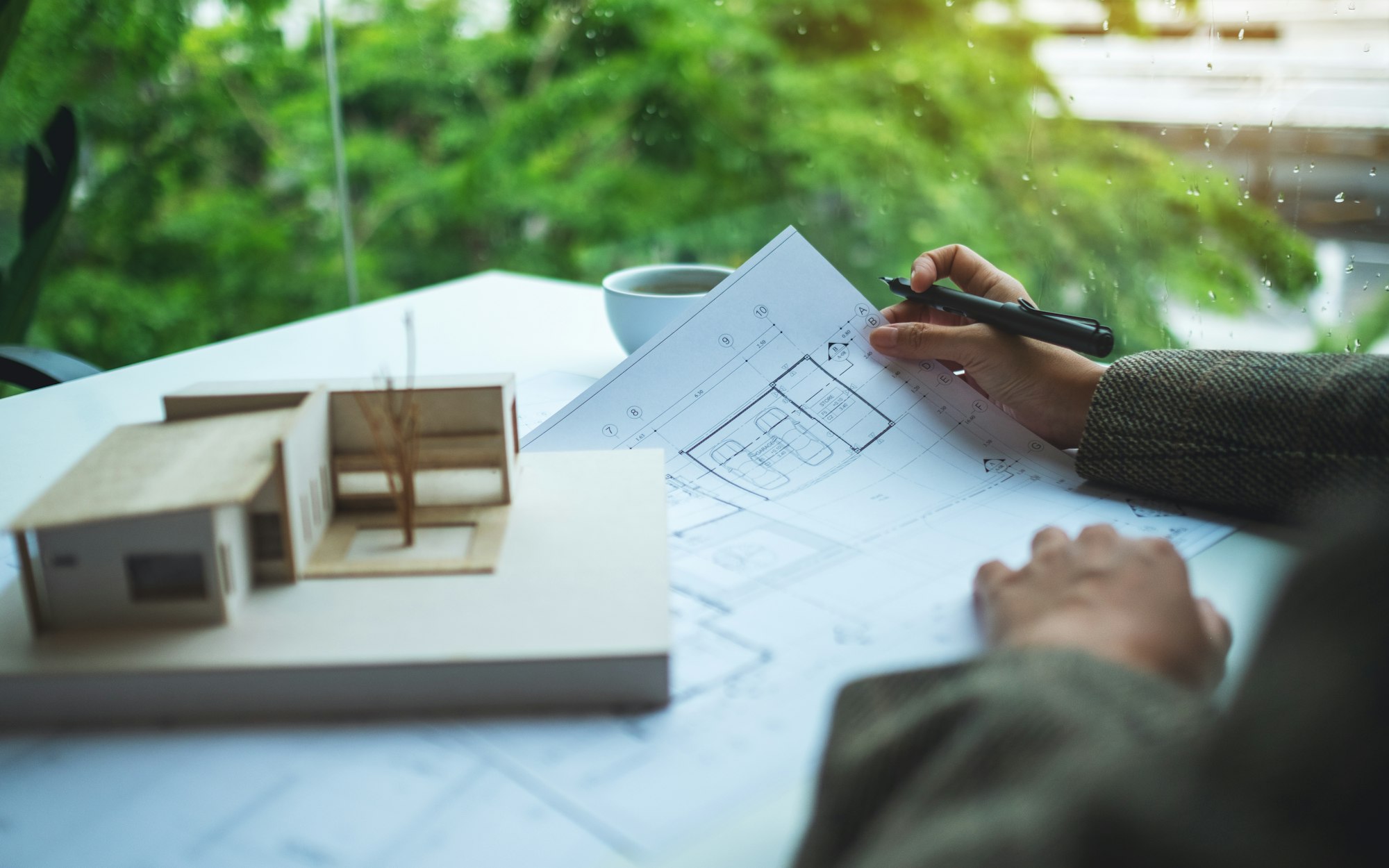 A female architect working on an architecture house model with shop drawing paper in the office